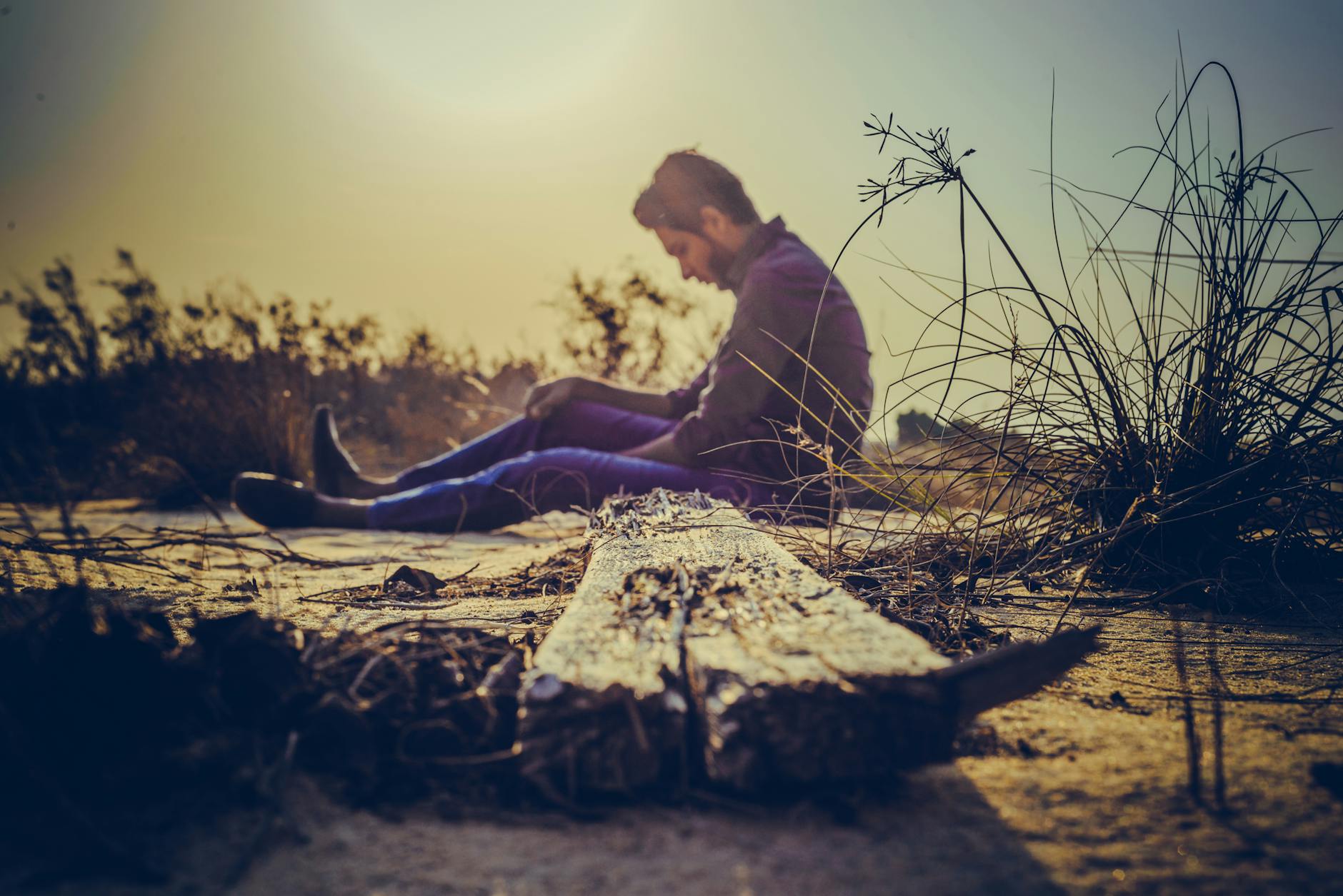 man sitting near brown wood plank